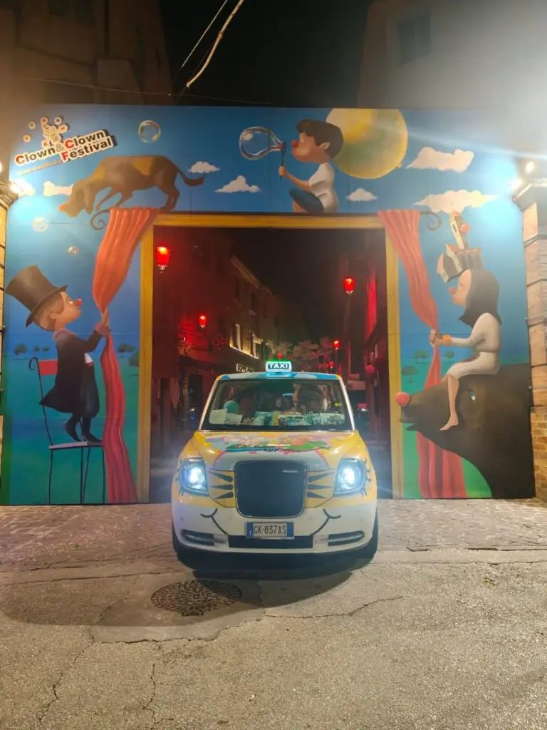 Il Taxi Milano 25 a Monte San Giusto sotto l’arco illuminato del Festival